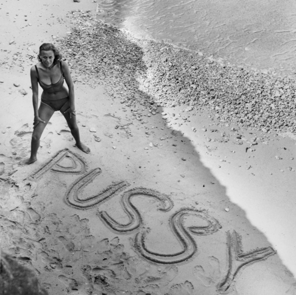 Terry O'Neill. English actress Honor Blackman on a beach, circa 1964. Spelt out in the sand is the name of her character, Pussy (Galore), from the James Bond thriller, 'Goldfinger'.